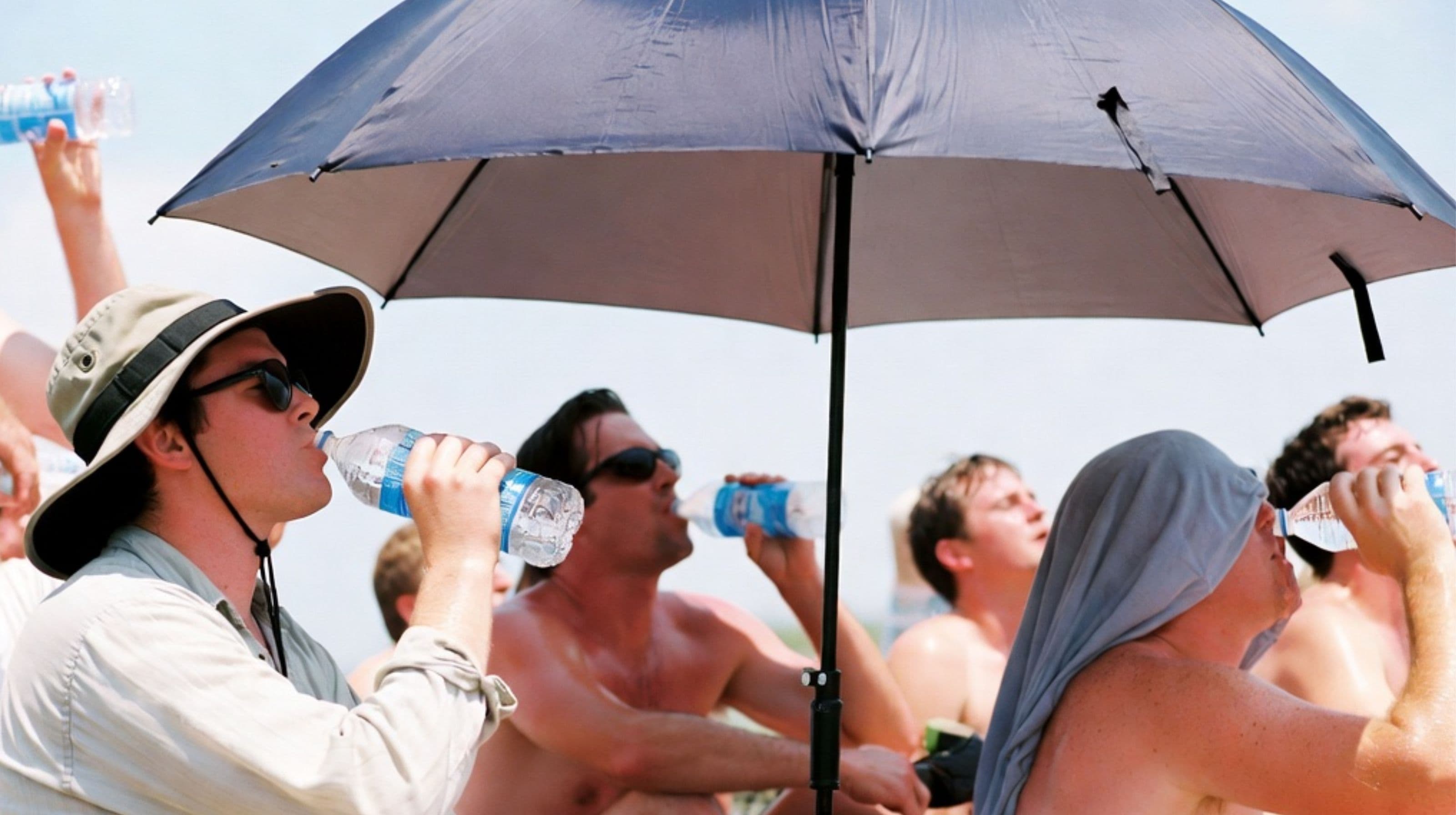 People staying hydrated and seeking shade during hot weather demonstrating heat safety practices